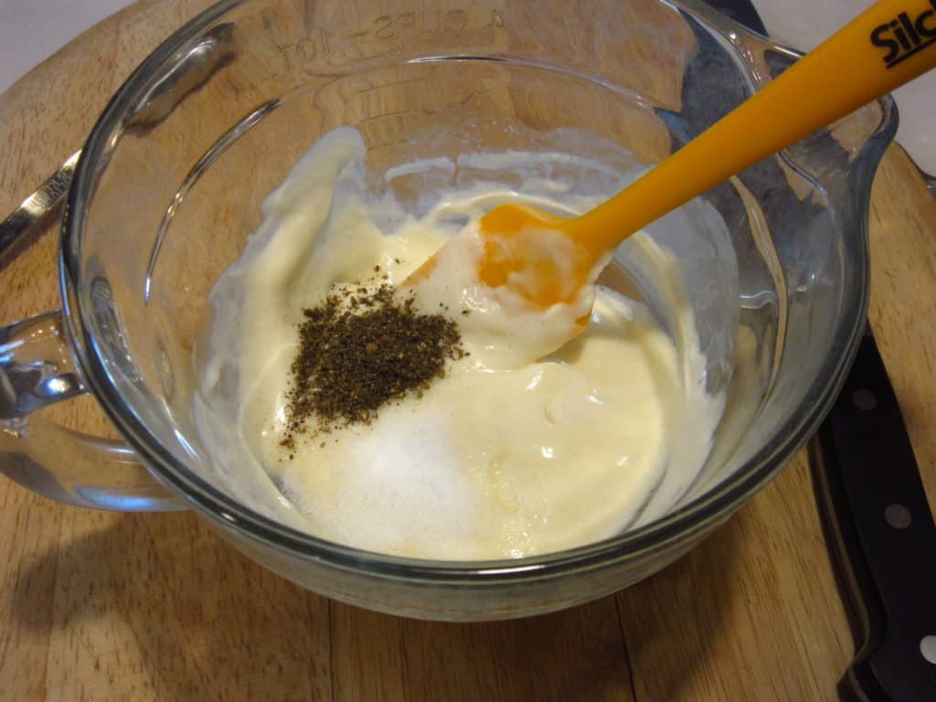 A glass measuring cup with dressing ingredients.