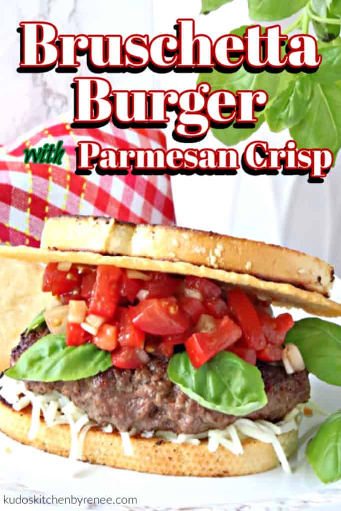 Closeup vertical image of a bruschetta burger with a Parmesan cheese crisp, fresh tomato relish, and basil leaves.