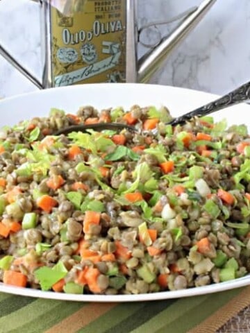 A white bowl filled with French lentil salad and a spoon.