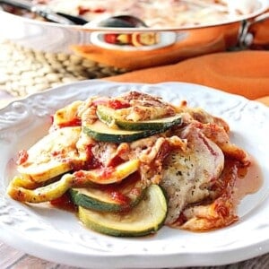 A white plate filled with a serving of Layered Zucchini Parmesan with melted cheese.