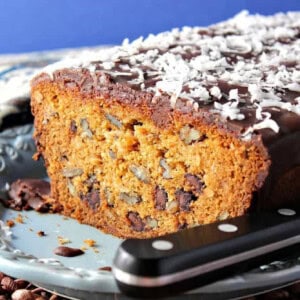 A chocolate chip dessert loaf on a platter with a knife.
