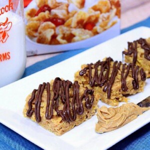 Tiger Paws Cereal Bars on a white plate with a knife and peanut butter.