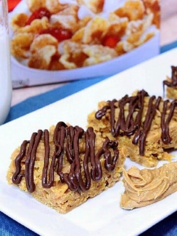 Tiger Paws Cereal Bars on a white plate with a knife and peanut butter.