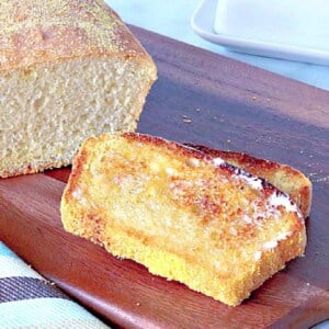 Two slices of toasted English Muffin Bread on a wooden cutting board.