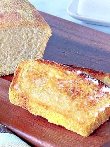 Two slices of toasted English Muffin Bread on a wooden cutting board.