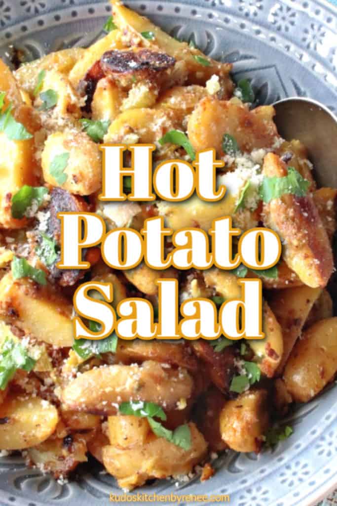 Very closeup photo of hot potato salad with Parmesan cheese and chopped parsley with graphic title text overlay.