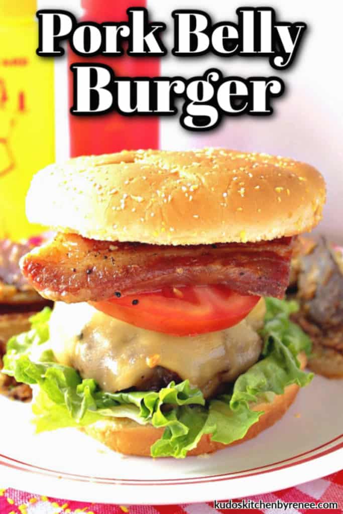 Closeup photo of a pork belly burger with lettuce, tomato, and pork belly.