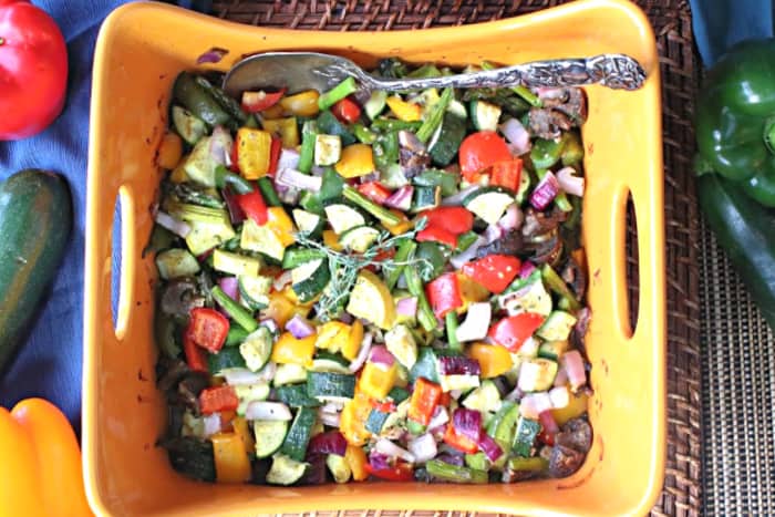 Overhead photo of a casserole filled with colorful roasted summer vegetable medley featuring bell peppers, zucchini, onion, and summer squash.