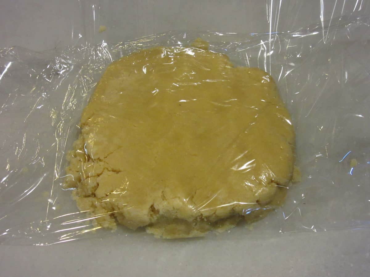 One pie dough disc being wrapped in plastic.