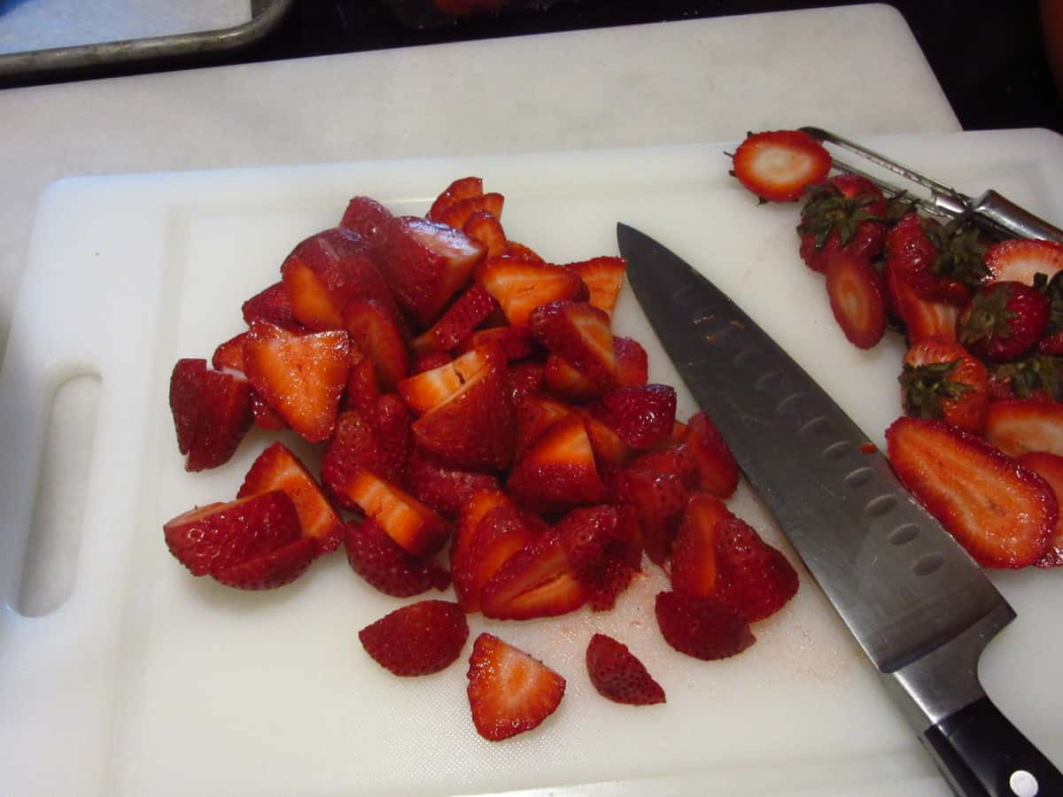 A knife and fresh strawberries on a cutting board.
