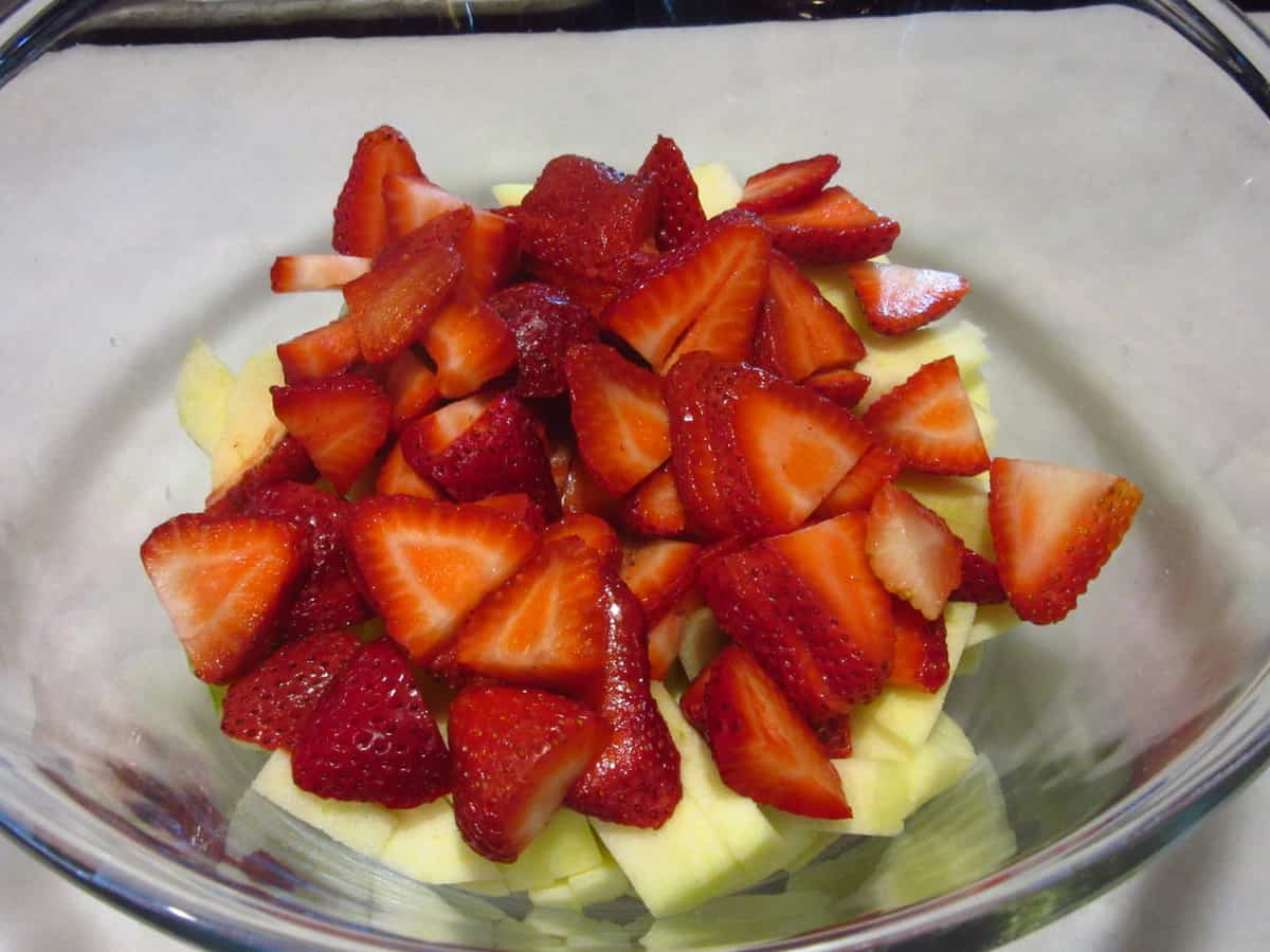 Fresh diced apples and strawberries in a glass bowl for making pie.