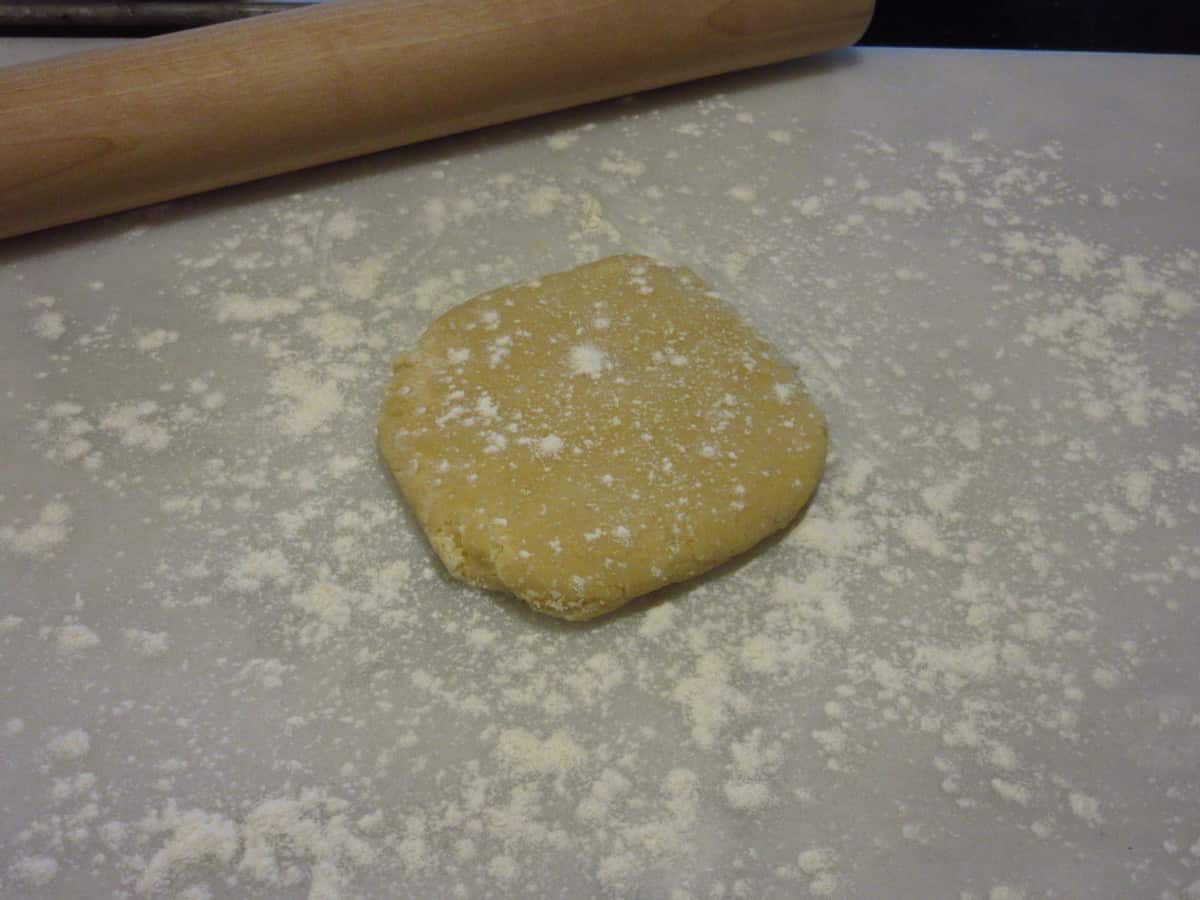 A pie dough disc on a floured surface.