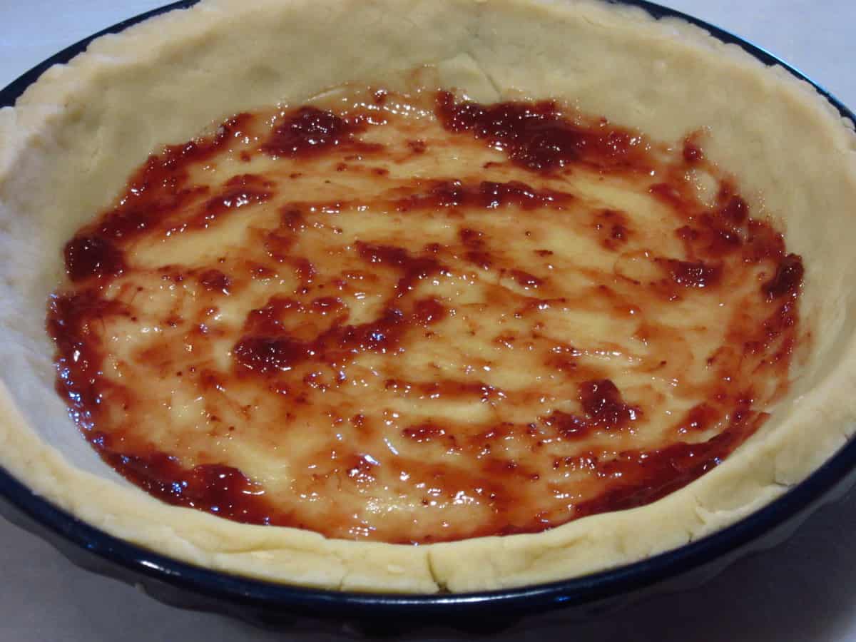 Strawberry jam on the bottom of an unbaked pie crust.
