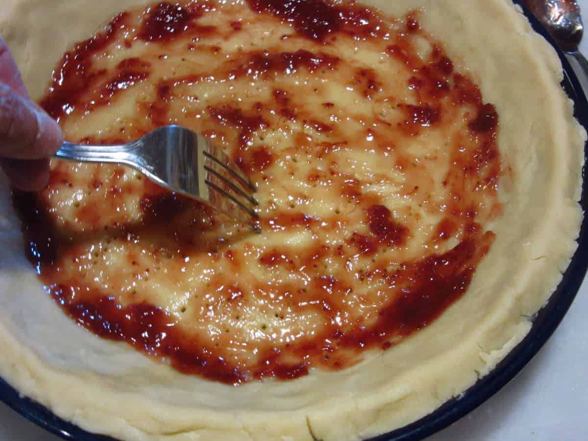 Strawberry jam in the bottom of a pie crust.