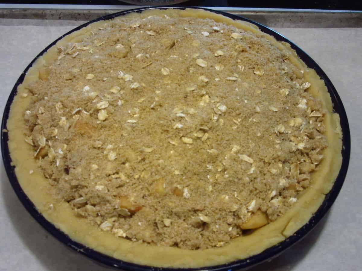 An unbaked Strawberry Apple Pie with a streusel topping.