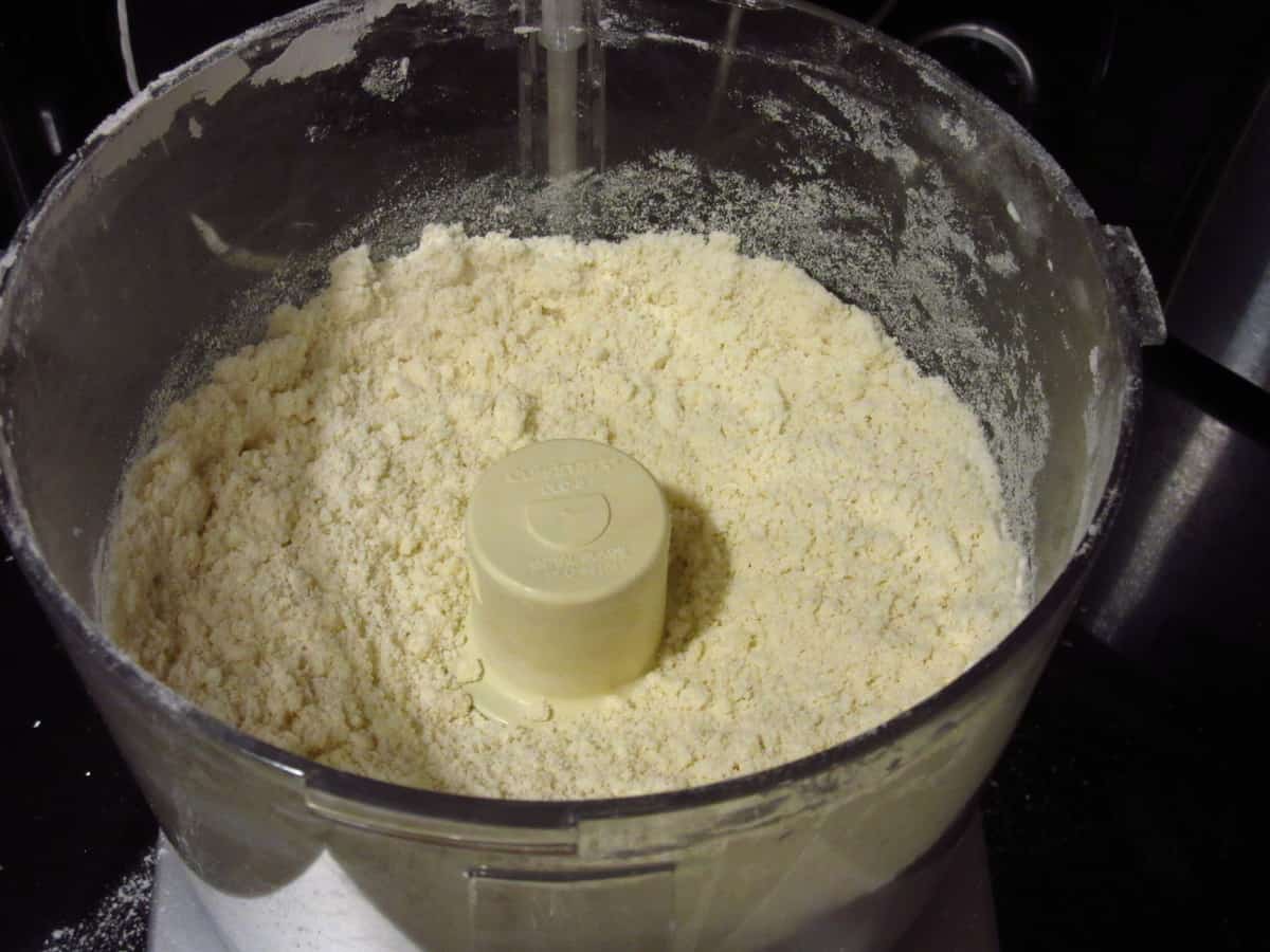Pie dough crumbles in a food processor.