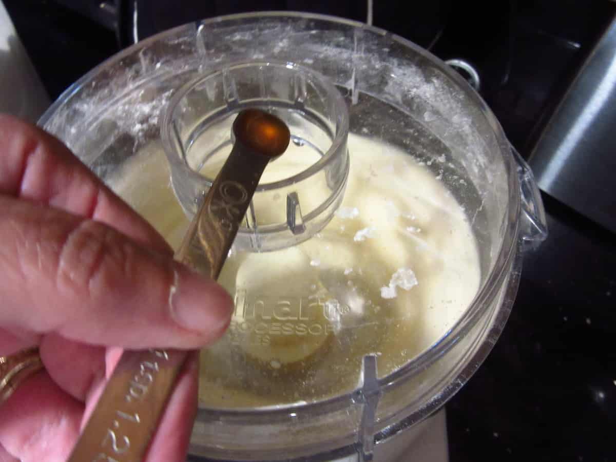 Vinegar being added to a food processor for making pie dough.