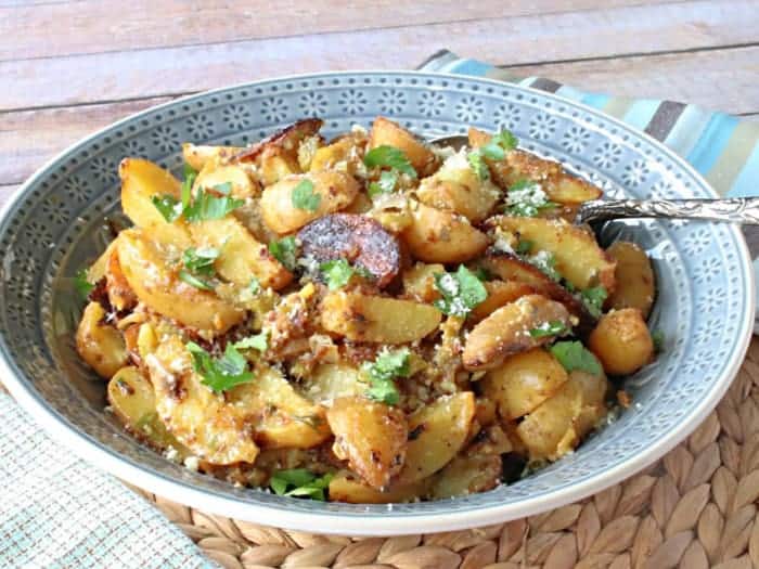 A blue bowl filled with hot potato salad and garnished with parsley for a bbq side dish recipes roundup