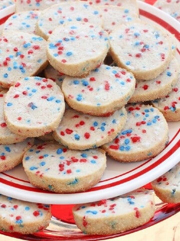 A platter filled with Cream Cheese Cookies with red, white, and blue sprinkles inside.