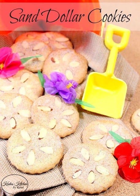 A pile of sand collar cookies coming out of a plastic bucket with a shovel.