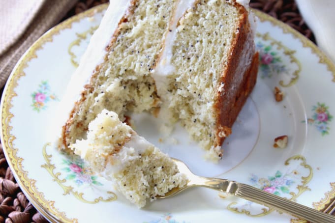 A closeup of a slice of banana poppy seed cake on a pretty china plate with a gold fork.