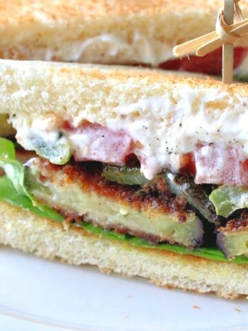 A Fried Eggplant Sandwich on toast with mayo, tomatoes, lettuce and green peppers.