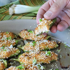 A hand holding a Crab Rangoon Jalapeno Popper with cream cheese and crab.