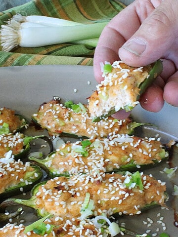 A hand holding a Crab Rangoon Jalapeno Popper with cream cheese and crab.