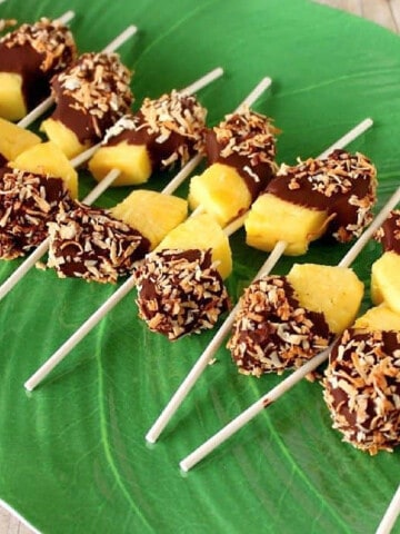 Frozen Pineapple Pops on sticks on a banana leave platter.