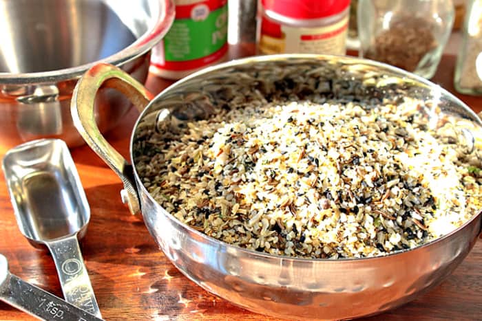 A small tin bowl with handles filled with homemade everything seasoning blend with measuring spoons on the side.