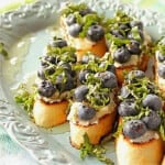 A light blue platter filled with Blueberry Basil Bruschetta topped with honey.