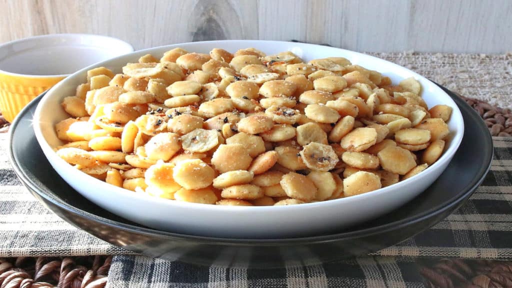A bowl of everything oyster crackers on a black and tan checked tablecloth