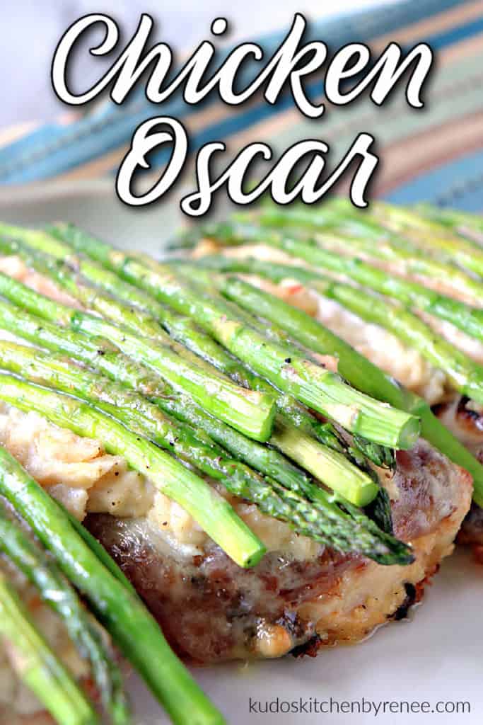 A vertical closeup photo of chicken Oscar with crab meat and asparagus spears on a platter the a title text over lay graphic