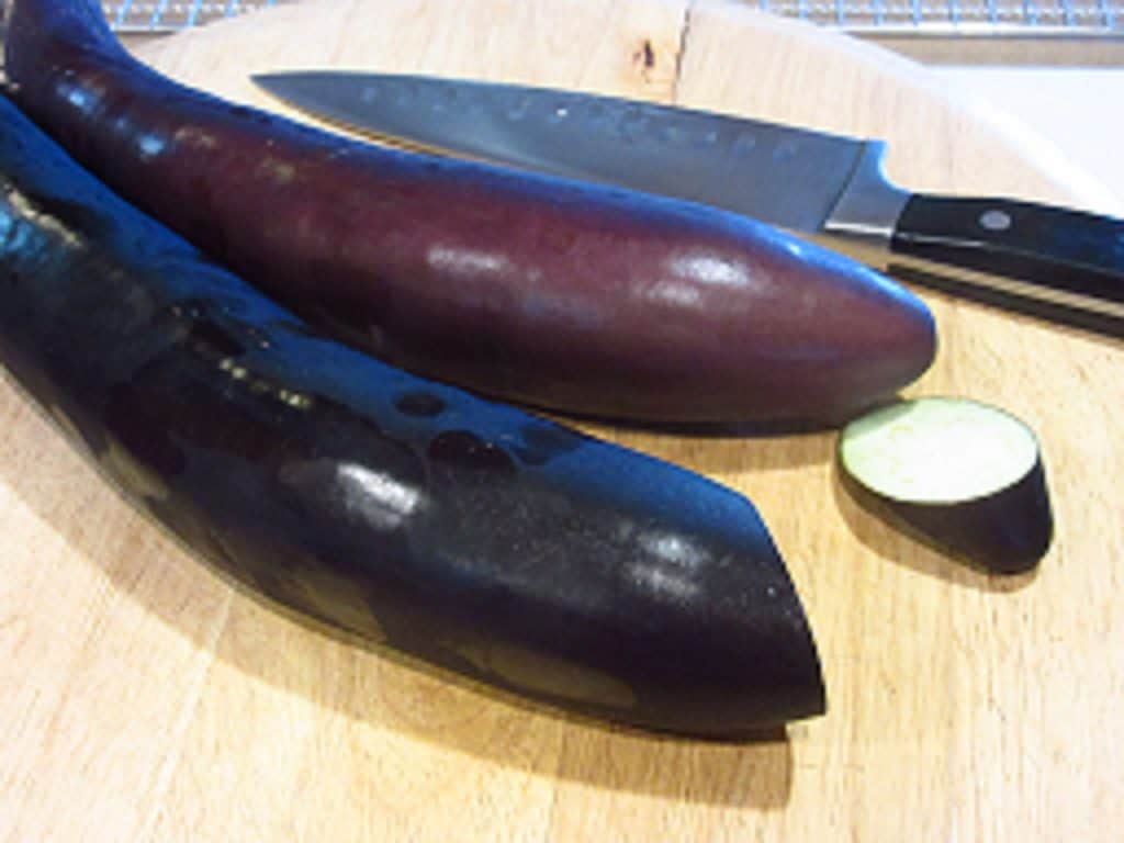 Eggplant on a cutting board with a knife.