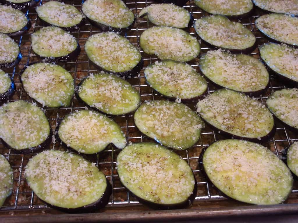 Eggplant slices topped with Parmesan cheese ready for the oven.