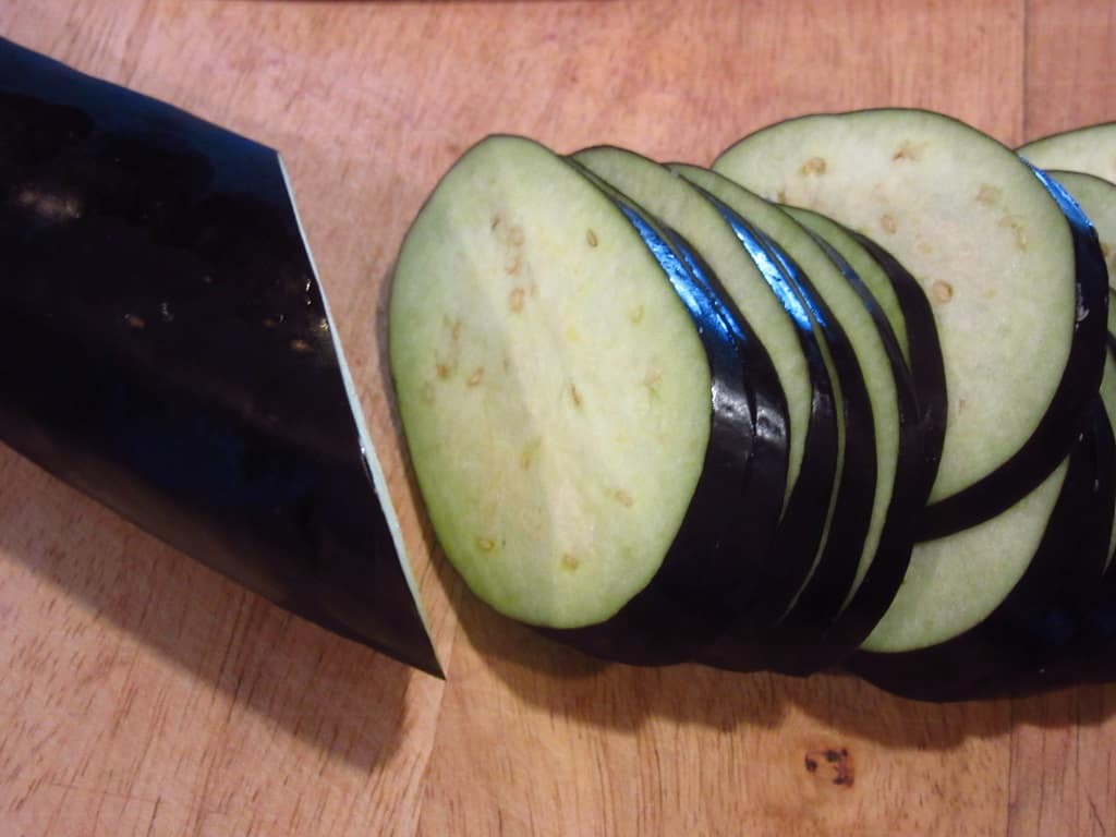 Sliced eggplant on a cutting board.