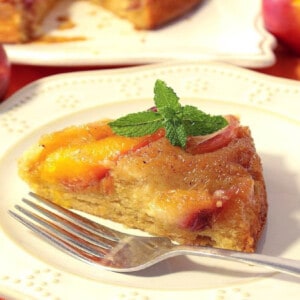 A slice of Nectarine Upside Down Cake on a white plate with mint.