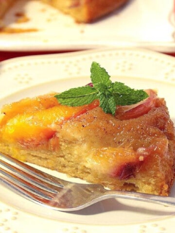 A slice of Nectarine Upside Down Cake on a white plate with mint.