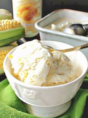 A serving bowl of No Churn Roasted Sweet Corn Ice Cream along with a spoon.