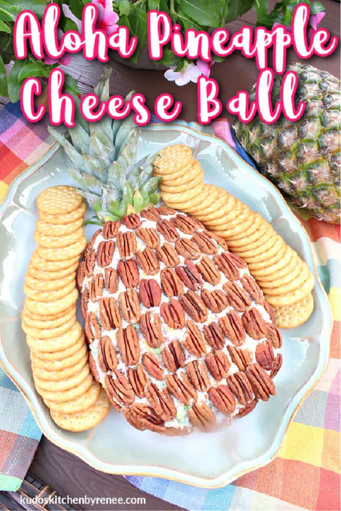 Overhead vertical photo of an aloha pineapple cheese ball with pecans and crackers on a serving platter with a title text overlay graphic