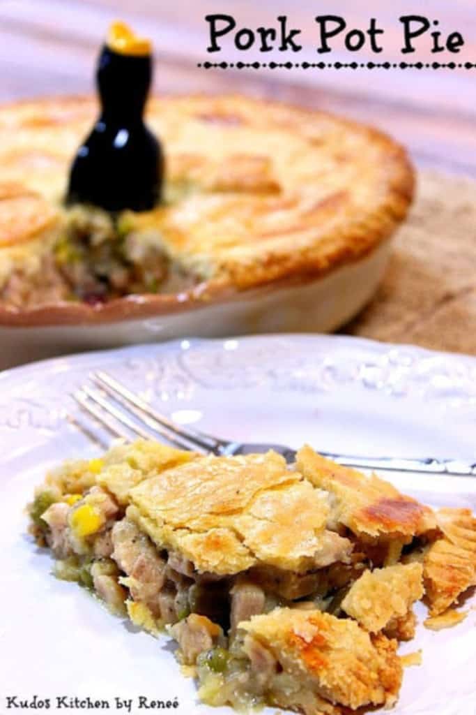 A vertical photo of a slice of pork pot pie in the foreground and the entire pie in the background.