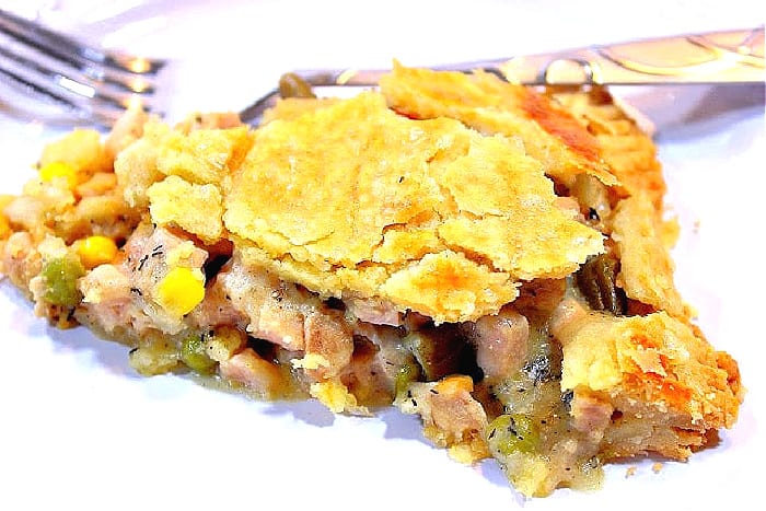 A closeup of a slice of pork pot pie on a plate the a fork.