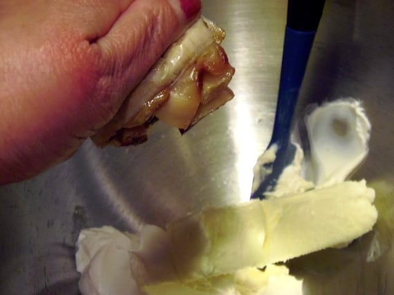 A bulb of roasted garlic being added to a stand mixer for making roasted garlic cip.