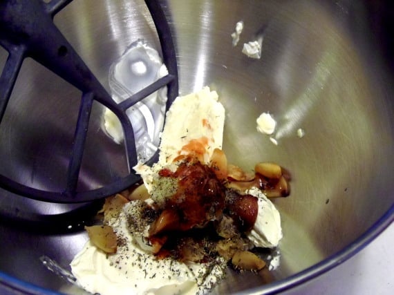 The paddle attachment in a stand mixer with all the ingredients for making roasted garlic dip.