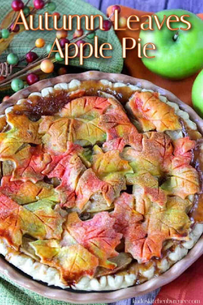 A vertical closeup photo of an apple pie with colorful autumn leaves crust and a title text overlay graphic