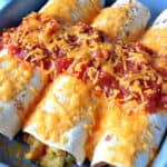 Three air fryer breakfast burritos in a blue casserole dish with salsa and cheese