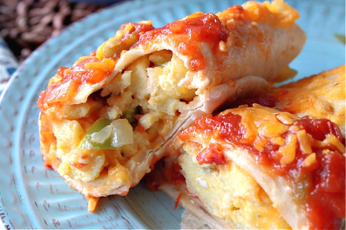 A closeup photo of the inside of an air fryer breakfast burrito with scrambled eggs, green pepper. shallots, and salsa