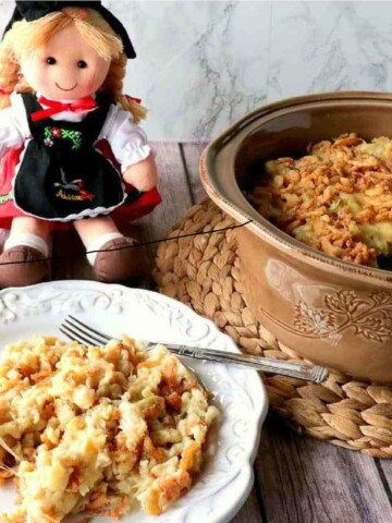 A plate of German Spaetzle Casserole in the foreground with a German doll in the background.