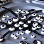 A pewter plate filled with Homemade Candy Eyeballs and a spider silhouette.