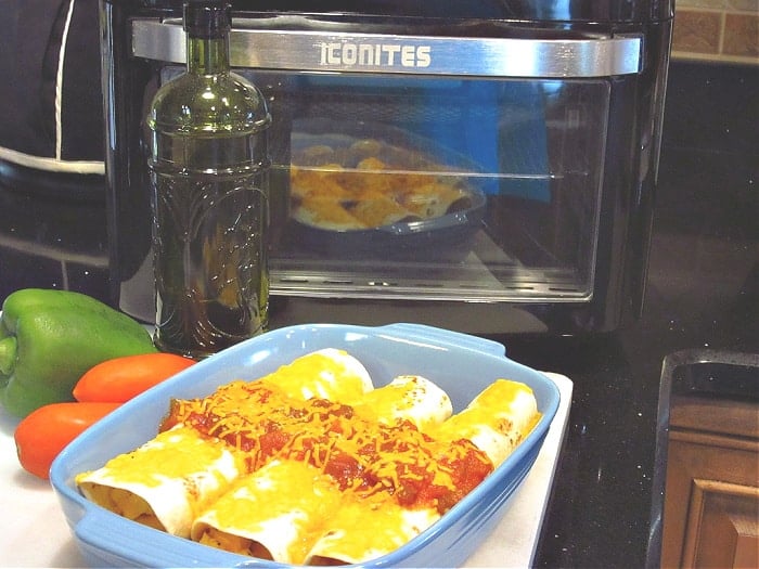 A horizontal photo of a dish of Air Fryer Breakfast Burritos in the foreground and an air fryer in the background.